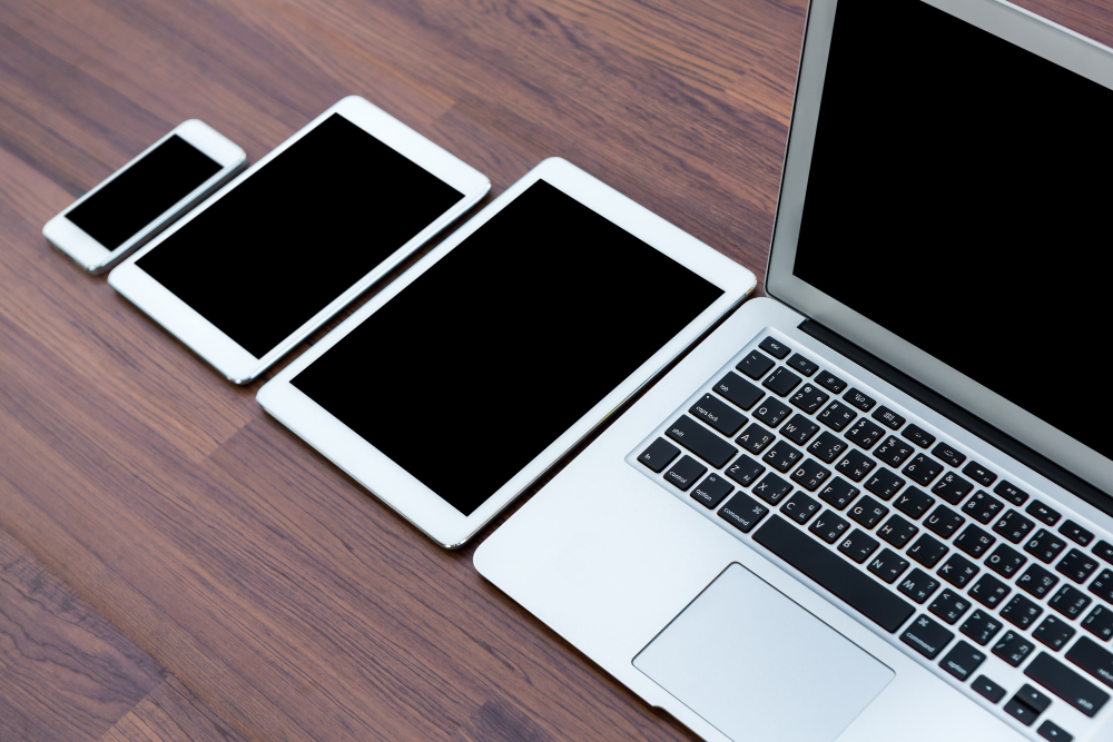 Celular, tablet e notebook dispostos em uma mesa de madeira: locação de dispositivos cresceu muito nos últimos anos